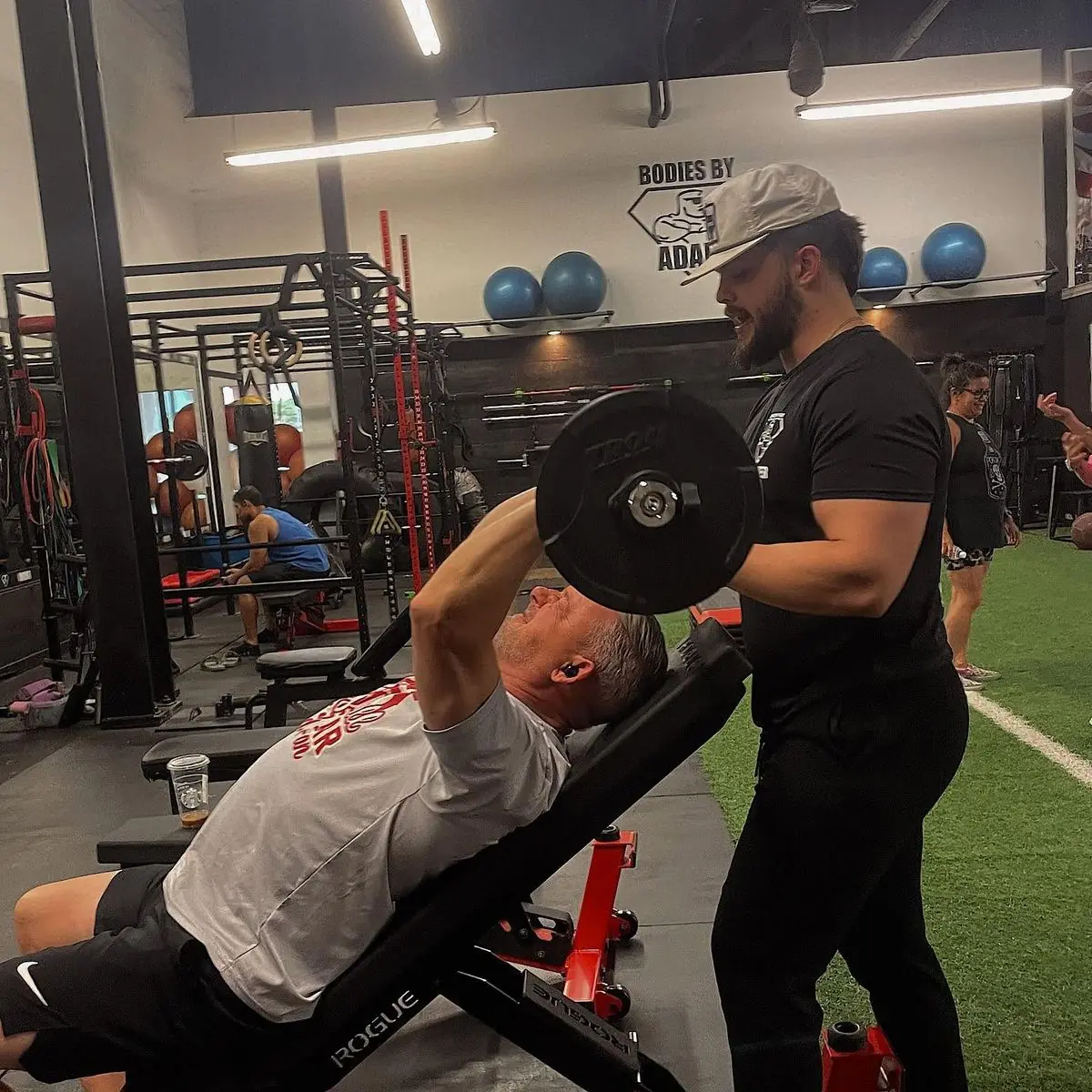 A coach spotting a client on the incline dumbbell press